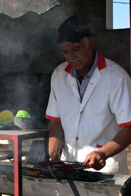Free A man grilling food outdoors, showcasing traditional street food preparation. Stock Photo