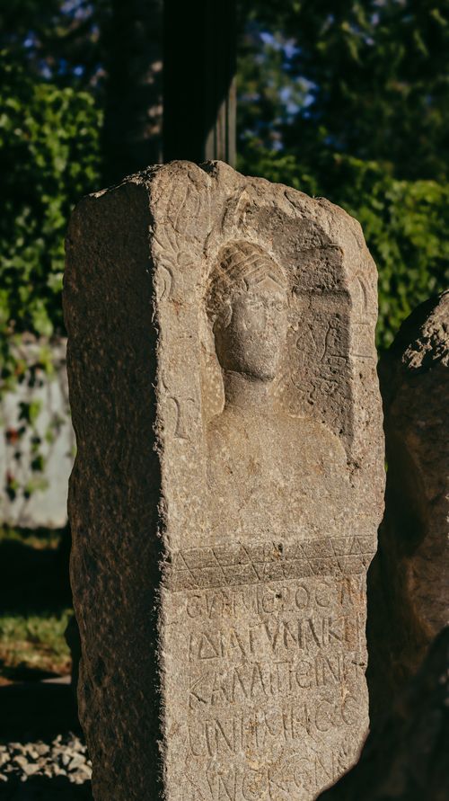 Free Historic stone relief with Greek inscription in outdoor setting, capturing warm sunlight. Stock Photo