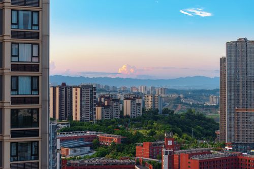 Free A picturesque cityscape featuring modern buildings and distant mountain ranges under a bright sky. Stock Photo