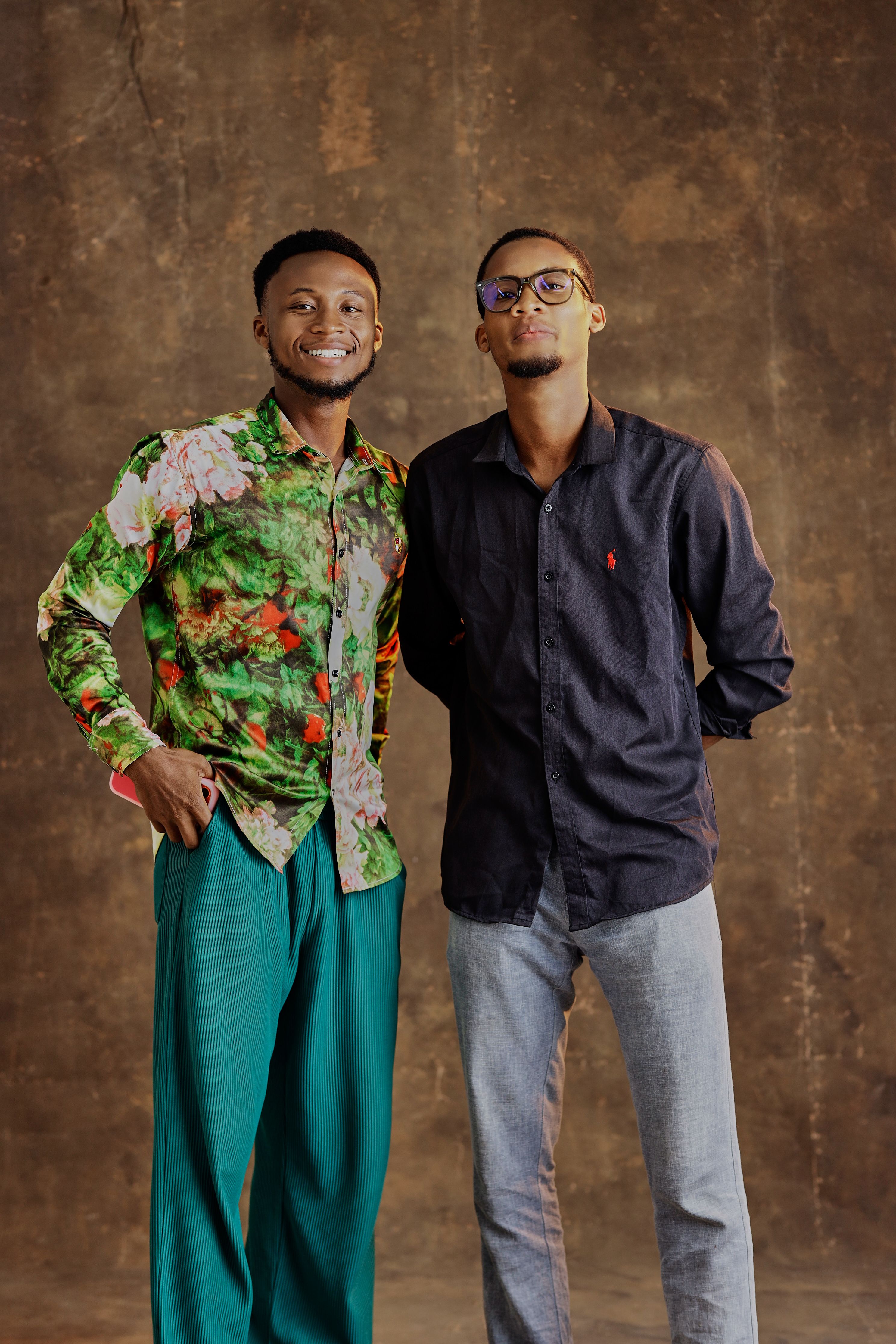Two stylish young adults showcase trendy fashion with unique outfits against a textured background.