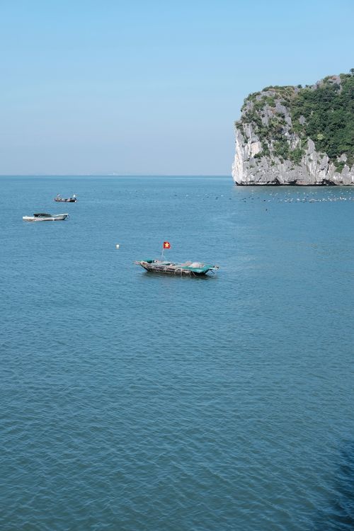 Free Peaceful seascape featuring boats and a stunning limestone cliff at daytime. Stock Photo