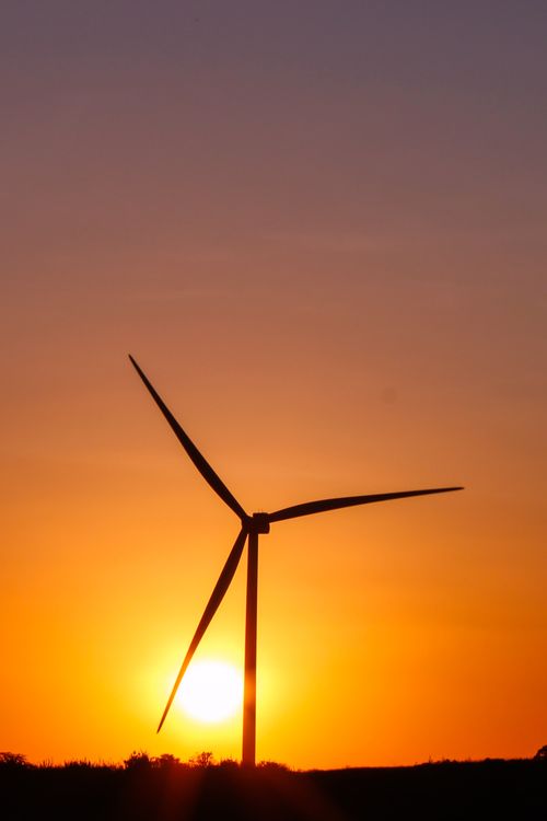 Free A wind turbine silhouetted against a vibrant sunset sky, capturing renewable energy beauty. Stock Photo
