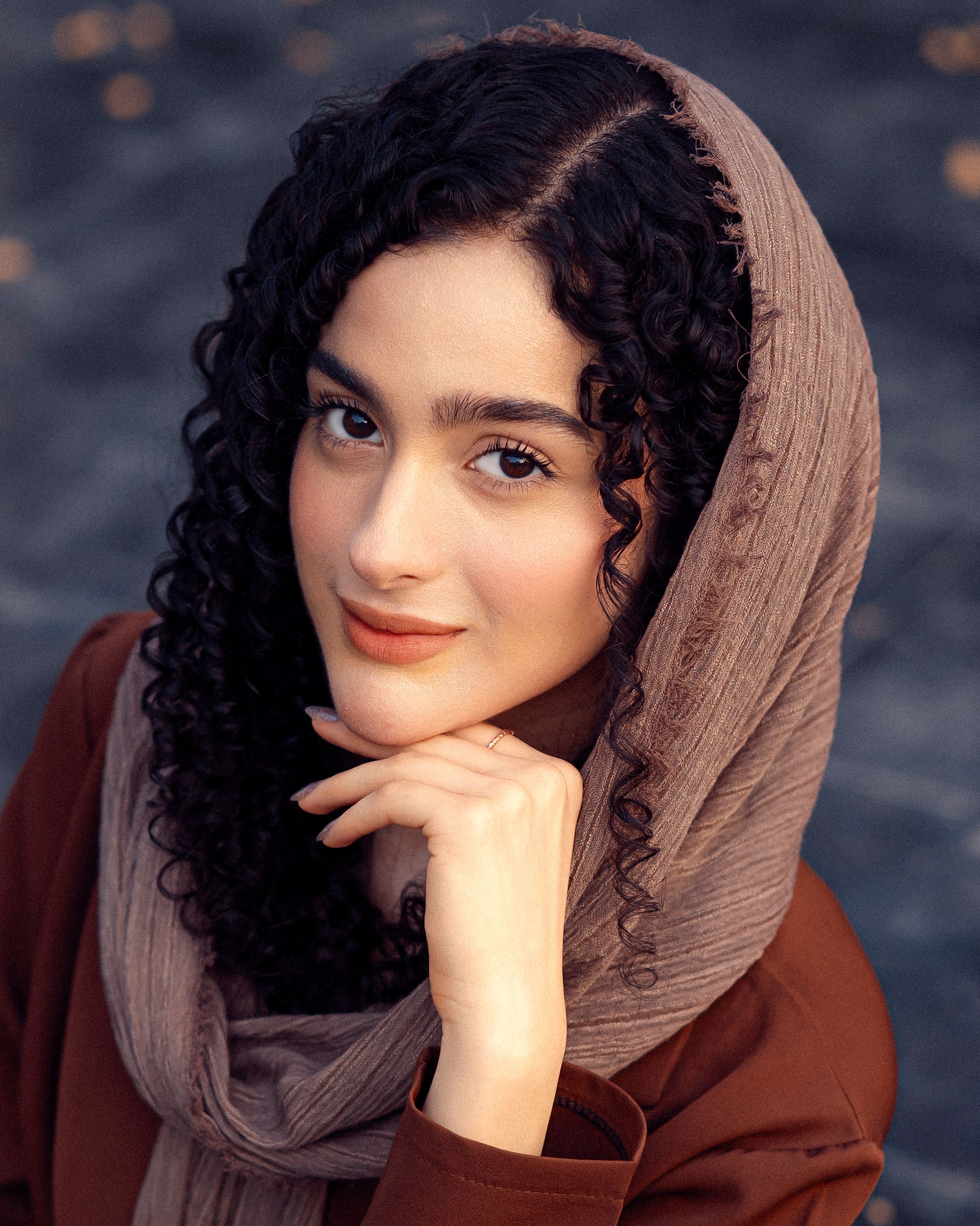Elegant portrait of a young woman with curly hair wearing a hijab, exuding grace and beauty.
