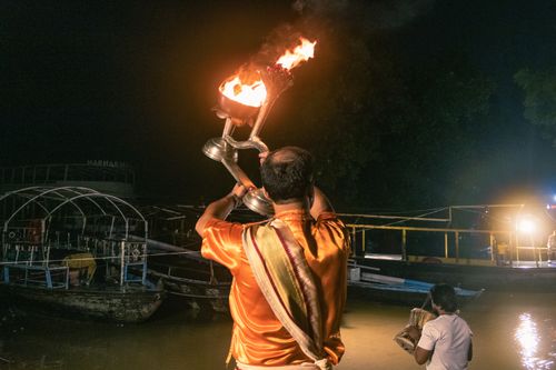 Free A nighttime river ceremony featuring a traditional fire ritual, emphasizing spiritual and cultural heritage. Stock Photo