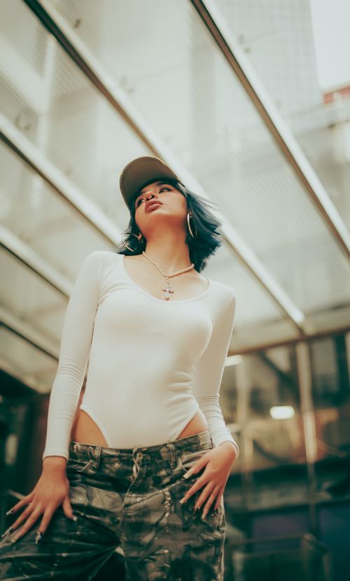 Free Young woman in stylish attire posing confidently in a modern urban environment. Stock Photo