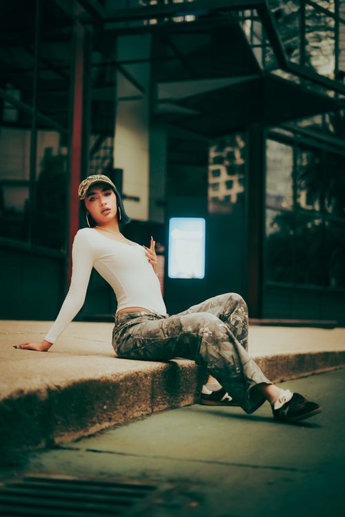 Free Fashionable young woman in streetwear poses on a city street corner. Stock Photo