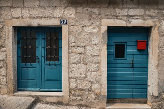 Rustic stone facade with vibrant blue doors and red mailbox, capturing Croatian charm.