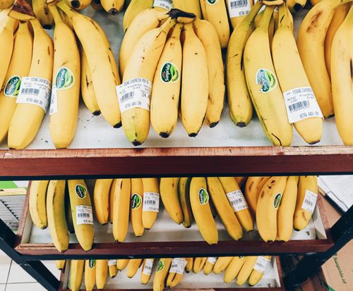 Free Multiple bunches of ripe bananas neatly arranged on supermarket shelves, ready for purchase. Stock Photo