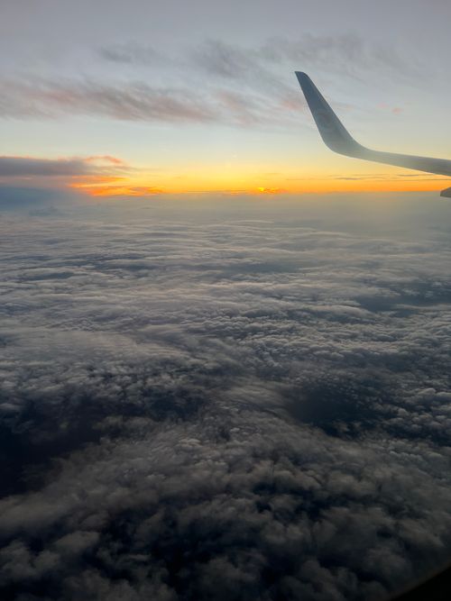 Free Stunning view of a colorful sunset from an airplane window, showcasing layers of clouds and the aircraft wing. Stock Photo