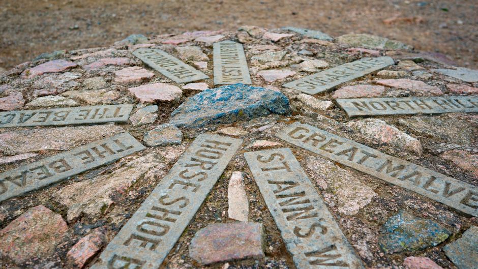 Stone directions marker on summit in Great Malvern, UK, showcasing points of interest.