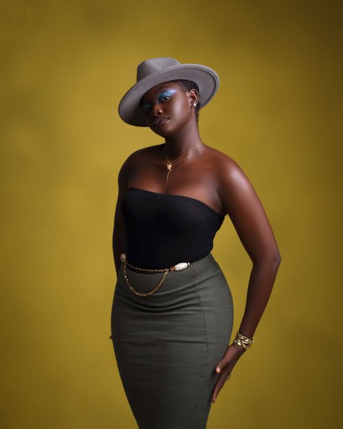 Free Elegant portrait of a woman wearing a hat and chic outfit against a vivid background. Stock Photo