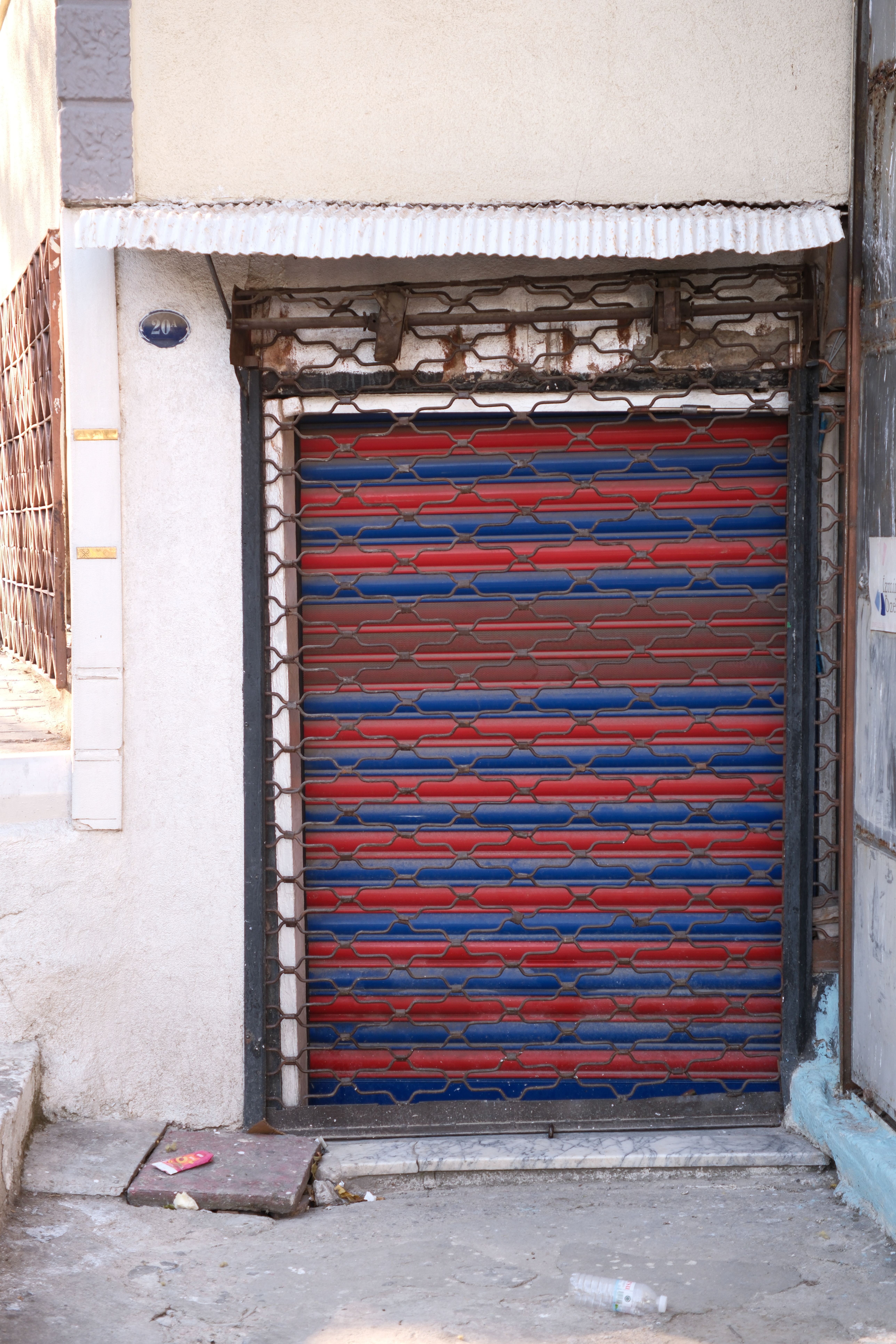 Vibrant blue and red shuttered doorway in İzmir, Türkiye, reflecting urban architecture.