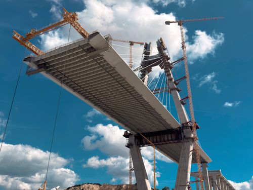 Free Tall bridge under construction with cranes against a blue sky. Stock Photo