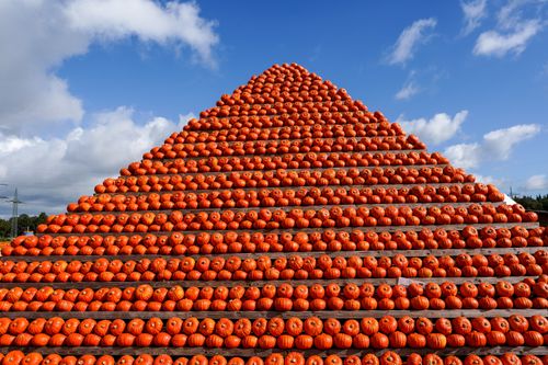 Free A striking pyramid of vibrant orange pumpkins against a clear blue autumn sky, captured outdoors in Hamburg. Stock Photo