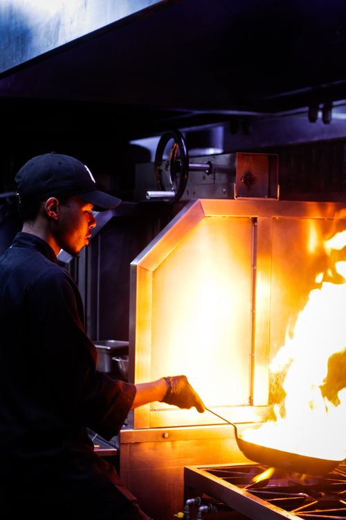Free Chef skillfully manages high flames in a dynamic restaurant kitchen setting. Stock Photo