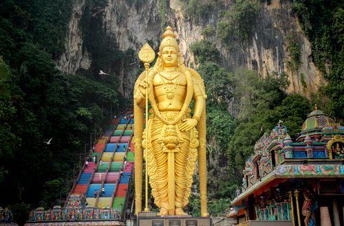Free Golden Lord Murugan statue with colorful steps at Batu Caves, a famous Hindu temple near Kuala Lumpur. Stock Photo