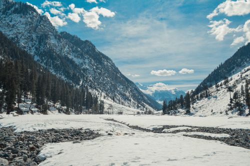 Free Majestic snow-covered mountains and a tranquil valley under bright blue skies, perfect for winter landscapes. Stock Photo