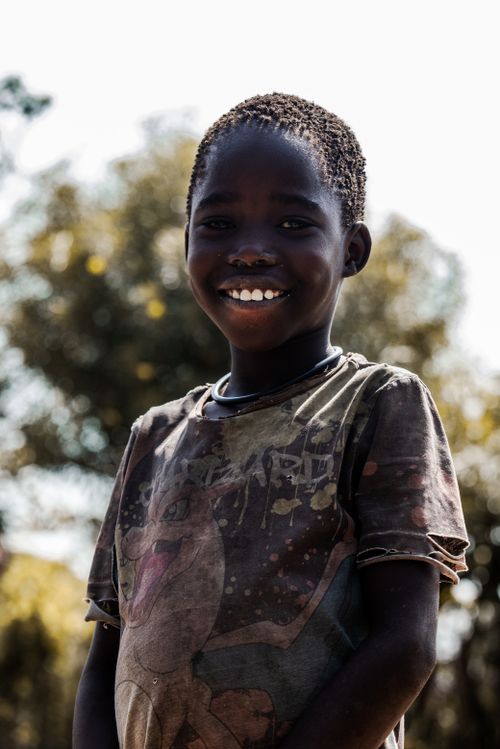 Free Portrait of a smiling African child outdoors with trees in the background. Stock Photo