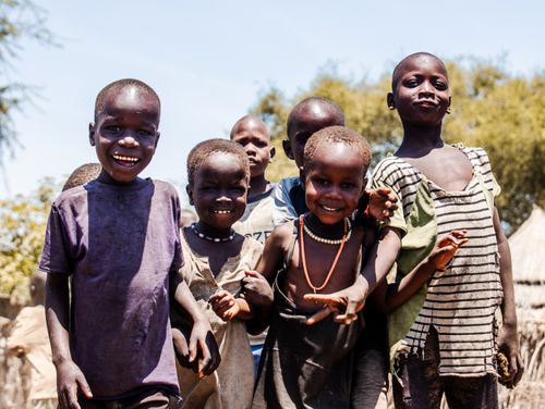 Free Group of smiling children playing outdoors under the bright sun, embodying joy and community. Stock Photo