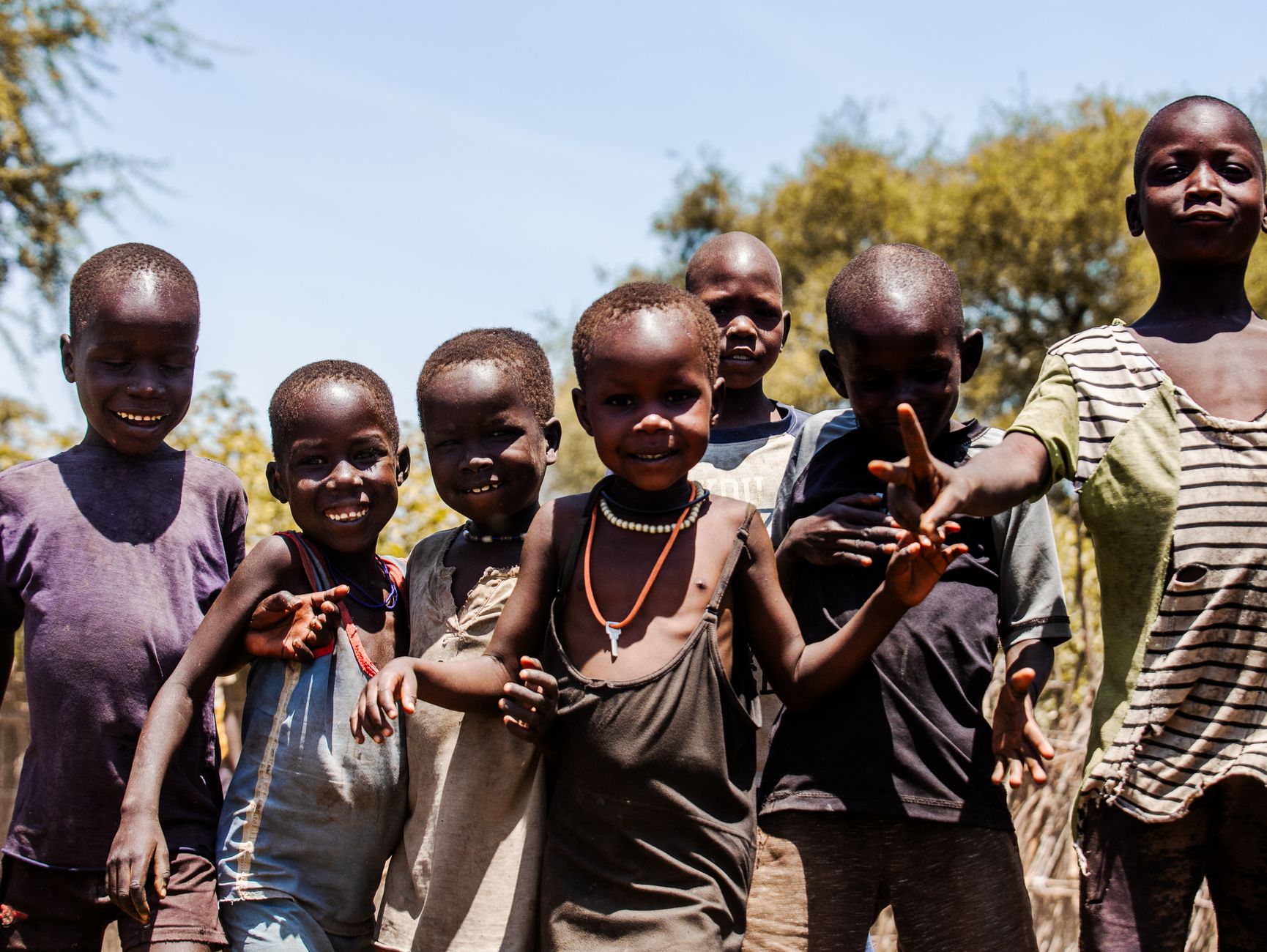 A group of smiling African children playing outdoors under the sunny sky, radiating joy and happiness.