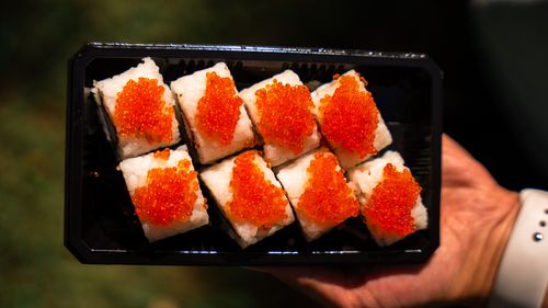 Free Top view of sushi topped with red caviar served in a tray, contrasting beautifully against a lush outdoor background. Stock Photo