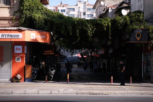 Free A shaded street in İzmir, Türkiye, showcasing local shops and greenery. Stock Photo