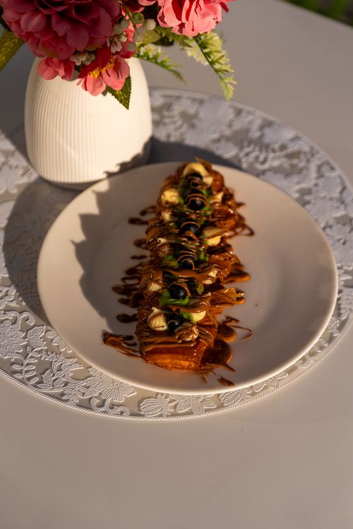 Free Delicious Turkish dessert elegantly plated with floral decor, captured in warm sunlight. Stock Photo