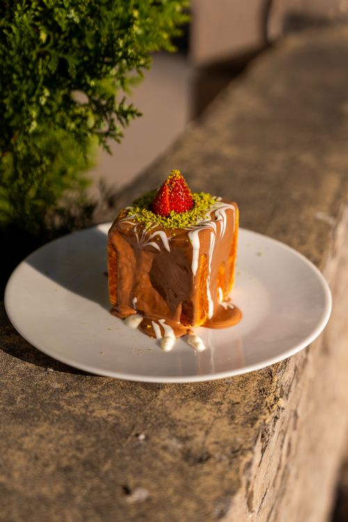 Free Close-up of a trilece cake topped with a strawberry and pistachios, on a white plate. Stock Photo
