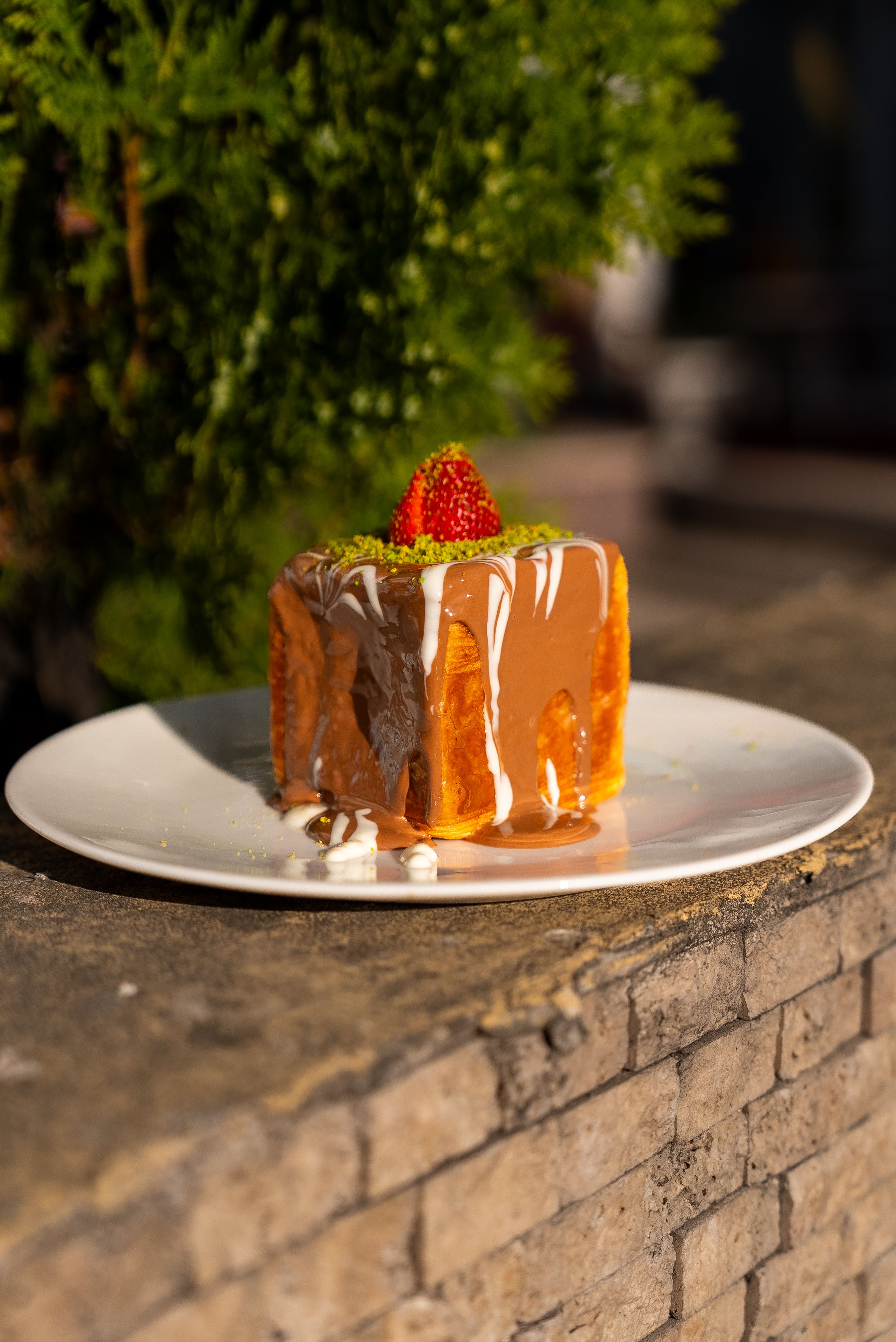 Close-up of a trilece dessert with strawberry and caramel sauce on a white plate outdoors in Niğde, Türkiye.