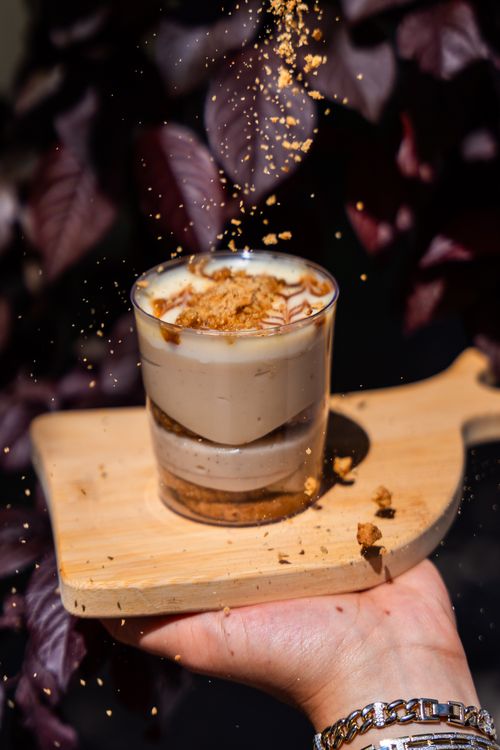 Free Hand holding a glass of trilece dessert topped with crumbs, capturing its texture and appeal. Stock Photo