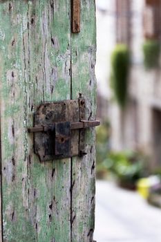 Close-up of a rustic green weathered door with an old metal latch.