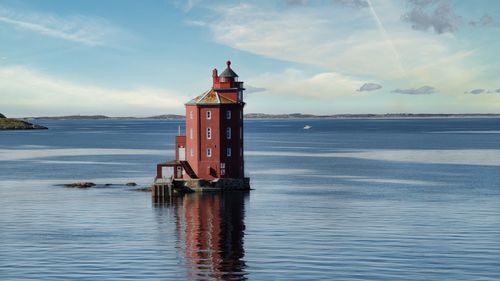 Free Scenic view of the red Henningsvær Lighthouse on a calm sea under a blue sky. Stock Photo