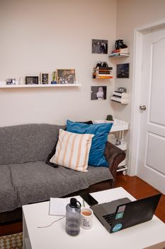 Modern home office with a laptop on a grey sofa, surrounded by decor and tech gadgets.