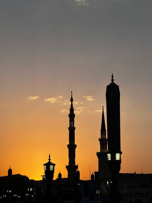 Free Mesmerizing silhouette of mosque minarets against a vibrant sunset sky. Stock Photo