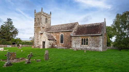 Free A scenic view of a historic church in the rural village of Almer, Dorset, England surrounded by greenery. Stock Photo