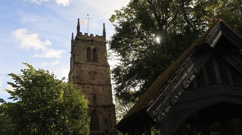 Free View of St. Chad's Church tower surrounded by trees in Wybunbury, England. Stock Photo