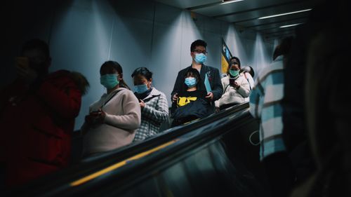 Free People wearing masks on an escalator in Shanghai during pandemic times. Stock Photo