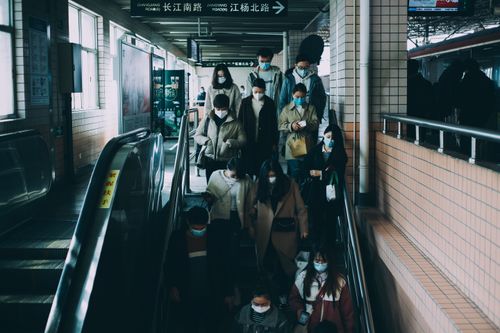 Free People in masks commuting at a train station in Shanghai during COVID-19. Urban transportation scene. Stock Photo