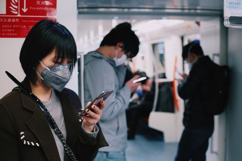 Free Adults wearing masks and using mobile phones on Shanghai subway amid COVID pandemic. Stock Photo