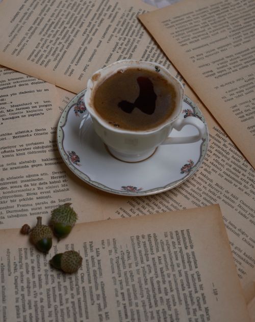 Free A charming scene with a coffee cup amidst aged book pages and acorns, evoking nostalgia. Stock Photo