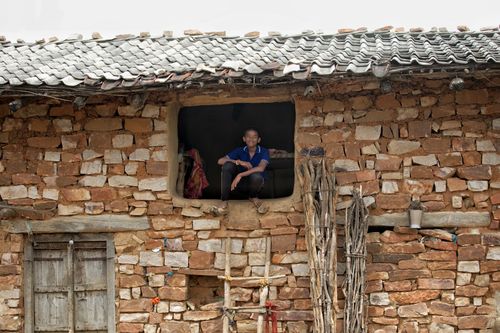 Free A young boy sitting at a window of a traditional stone house in Chitrakoot, India. Stock Photo