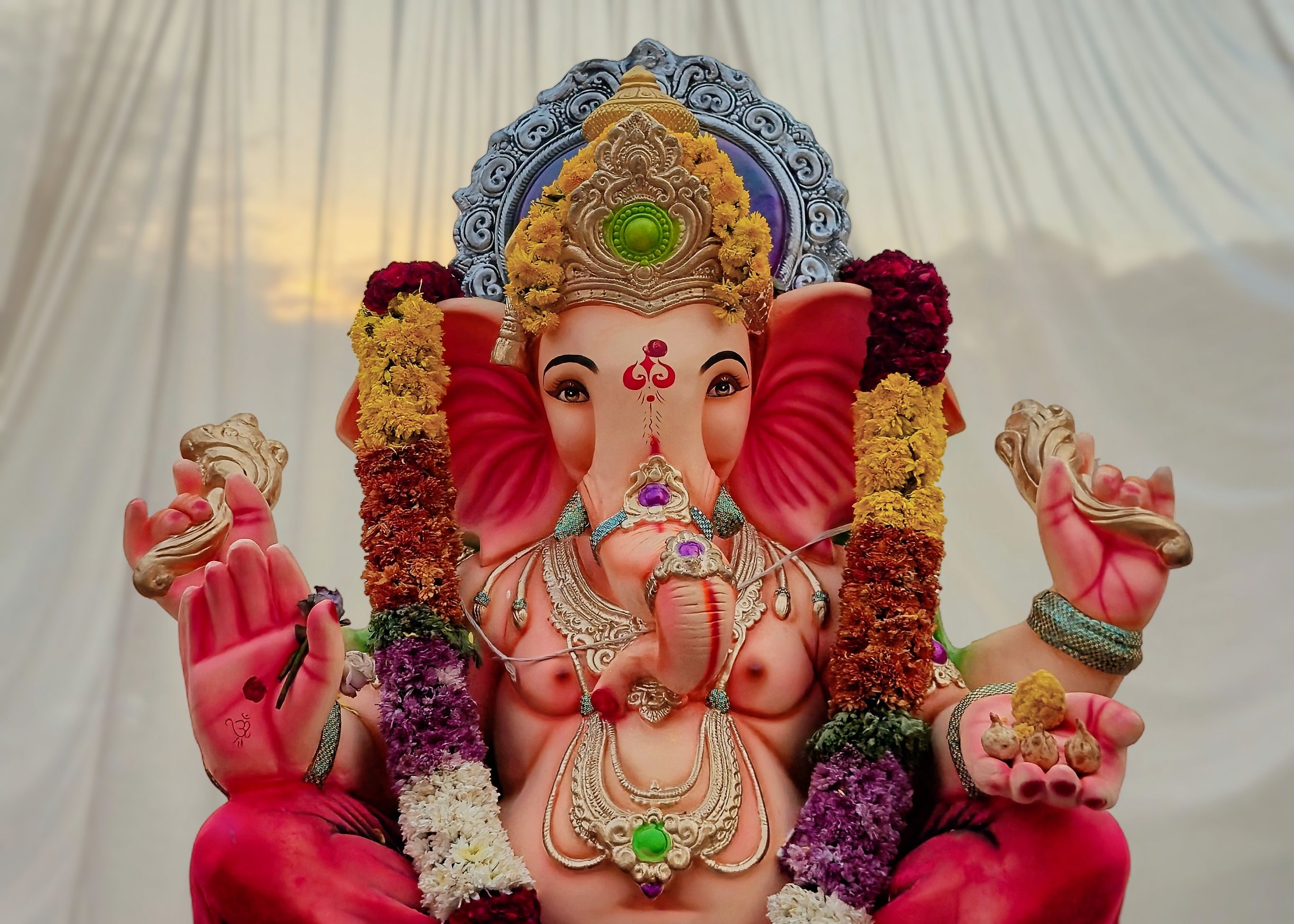 Colorful statue of Lord Ganesha adorned with a floral garland, symbolizing spirituality and art.