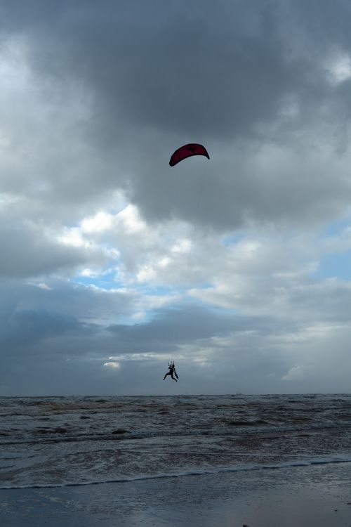 Free A kitesurfer gracefully navigates the windy skies above Amsterdam's waves, showcasing excitement and freedom. Stock Photo