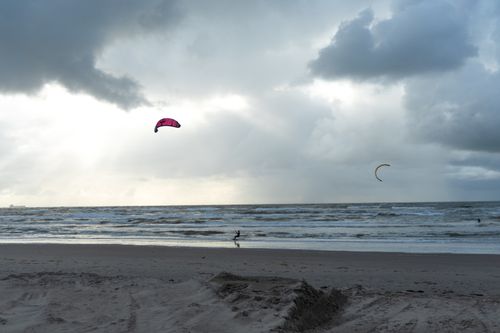 Free A kitesurfer rides the waves against a dramatic cloudy sky on a beach in Amsterdam, Netherlands. Stock Photo