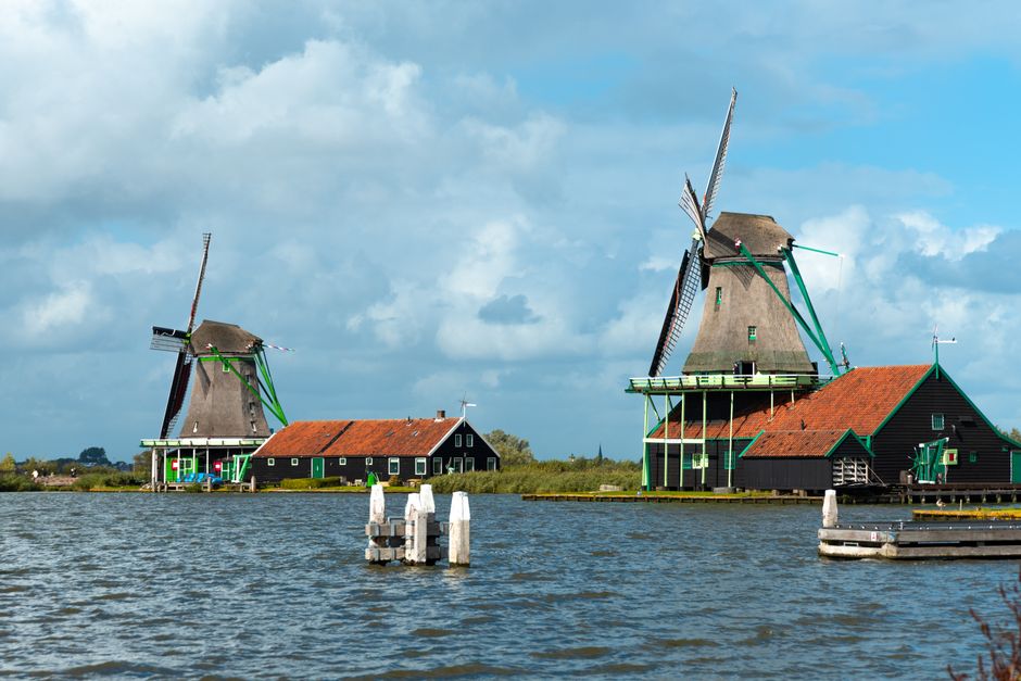 Scenic view of iconic Zaanse Schans windmills in Amsterdam under blue skies.