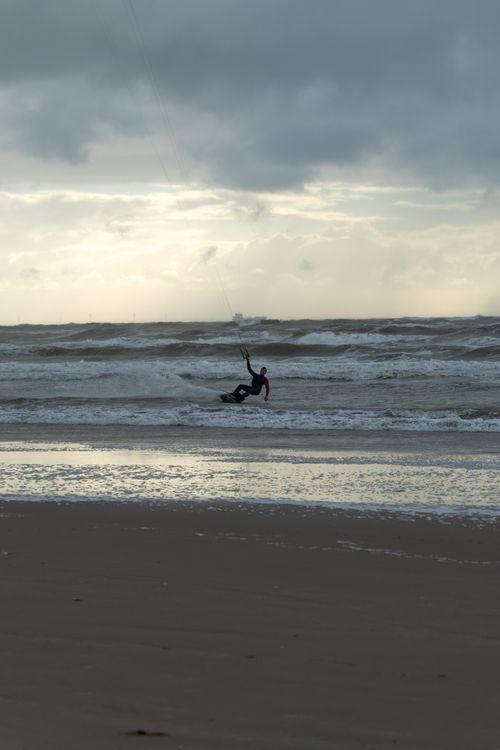 Free Kitesurfer riding waves on a cloudy day in Amsterdam's beach, Netherlands. Stock Photo