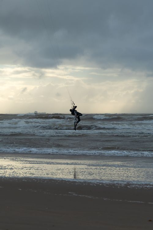Free A dynamic kitesurfer enjoying waves against a stunning Amsterdam beach sunset. Stock Photo