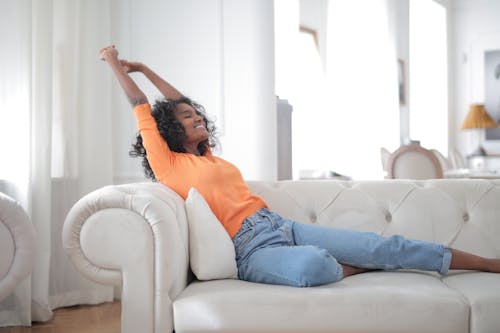 Free Happy African American female stretching on sofa Stock Photo