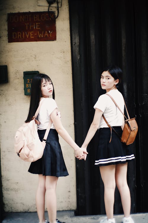 Girls in School Uniform Looking Back While Holding Hands Outside Building