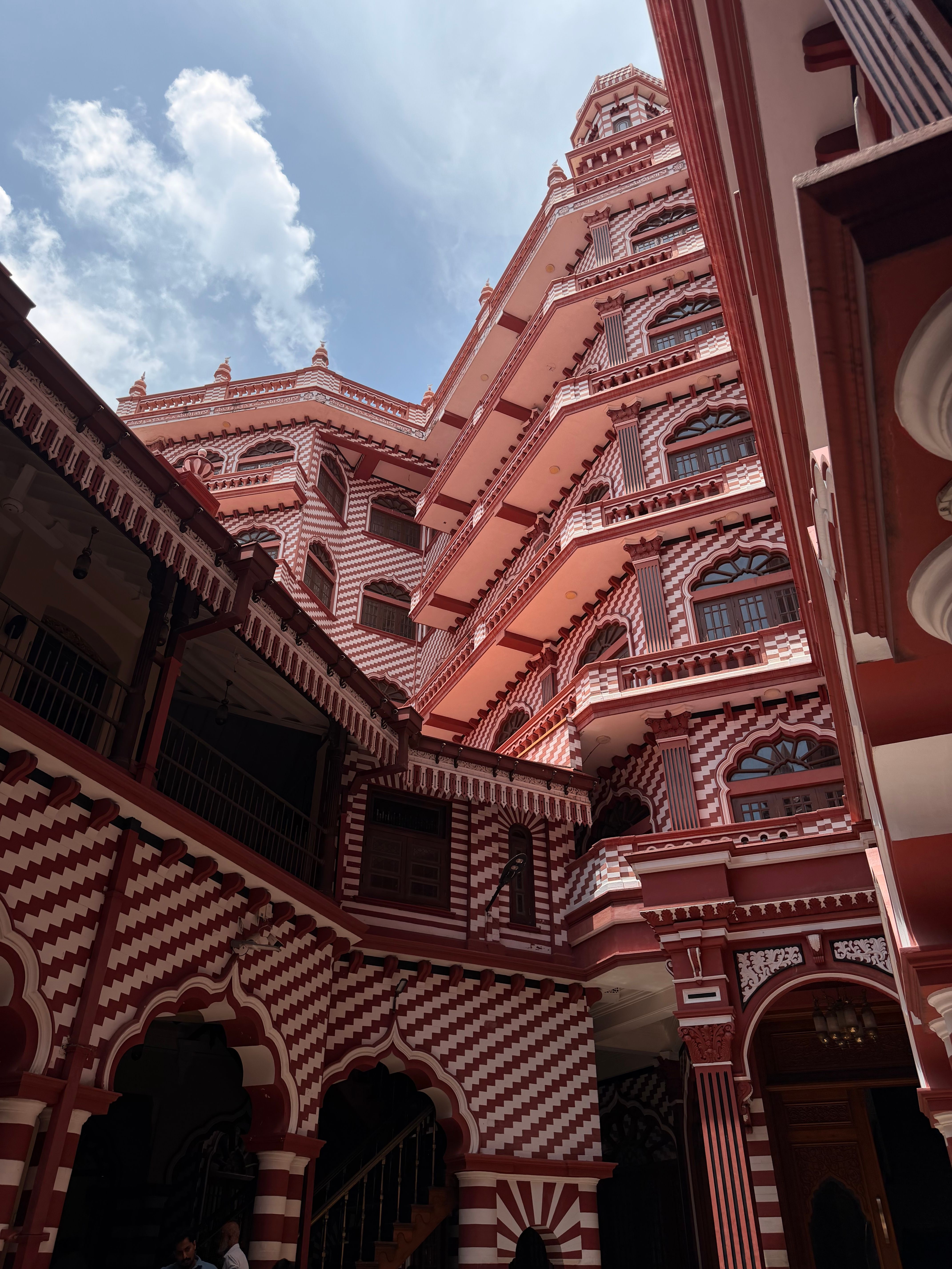 Stunning view of the red and white striped architecture of Jami Ul-Alfar Mosque in Colombo against a blue sky.